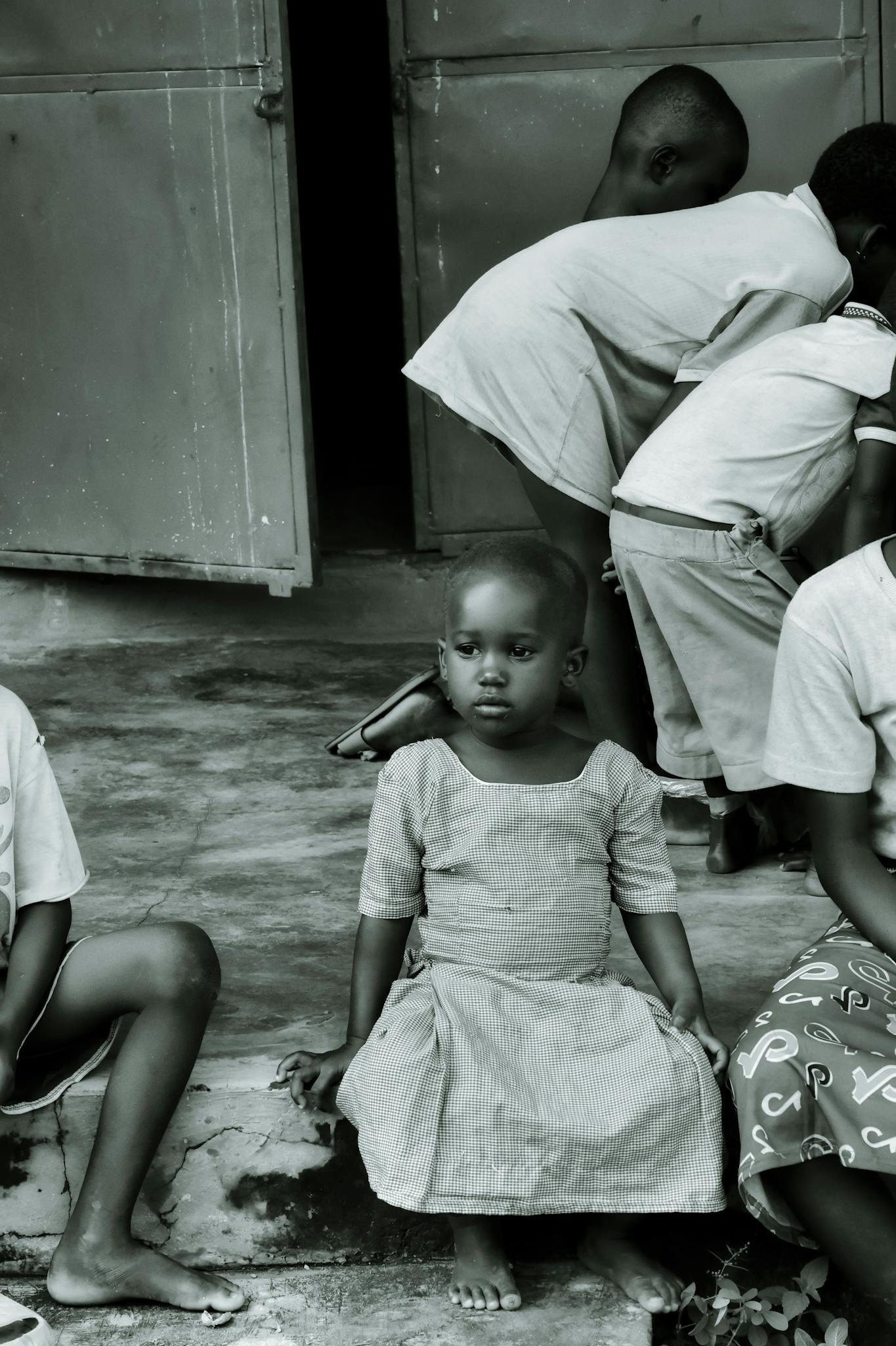 A poignant black and white photo of African children sitting together, capturing innocence and camaraderie.